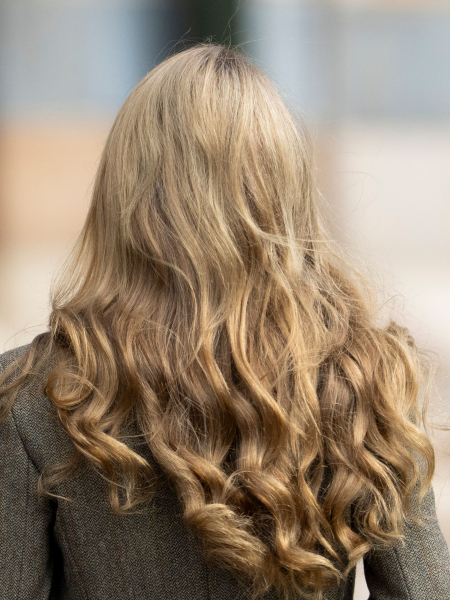 Kate Middleton is seen from behind. She has long blonde hair worn in curls.
